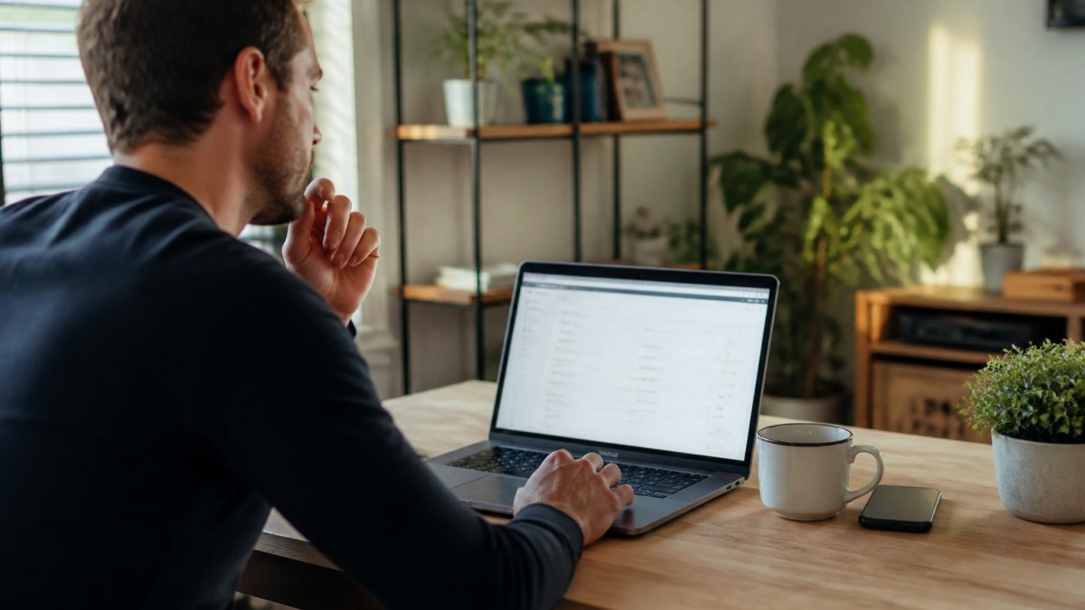 Persoon aan bureau analyseert snelheidsscores van WordPress hosting op een laptop in een thuiskantoor.